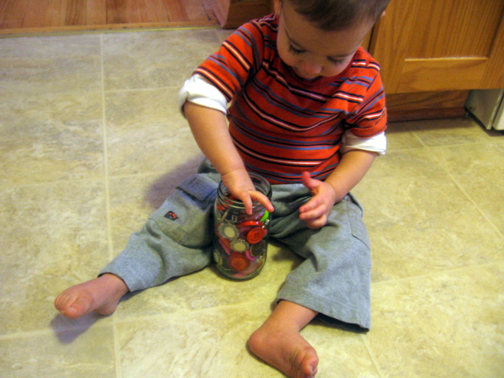 孩子试图把纽扣从罐子里拿出来