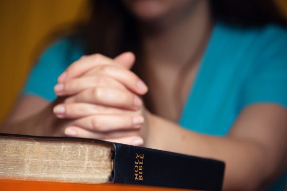 祈祷用手的女孩在150岁的圣经