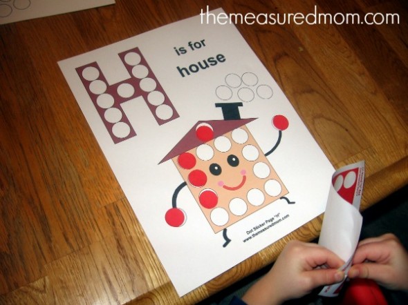 孩子把贴纸贴在字母H的工作纸上