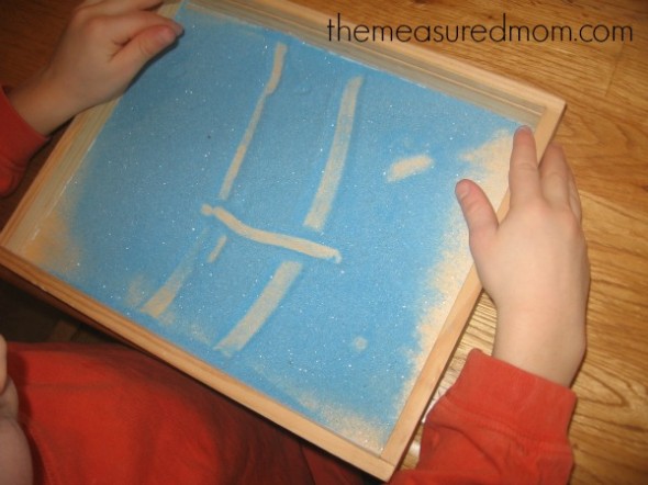 孩子用彩色的沙子做出字母H