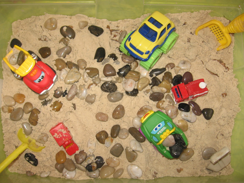 有汽车、石头和沙玩具的沙箱