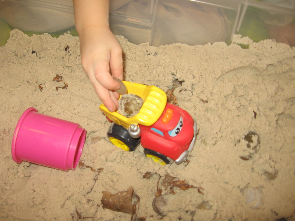 孩子驾驶玩具卡车在沙箱