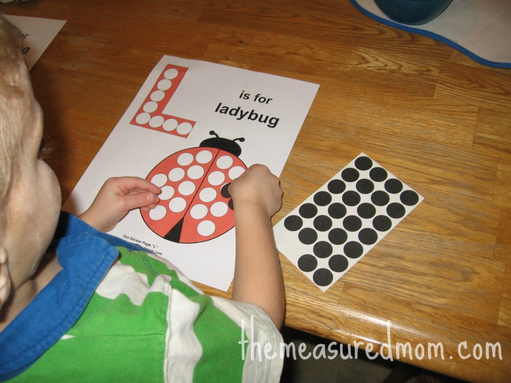 孩子把点贴纸贴在字母L的工作纸上