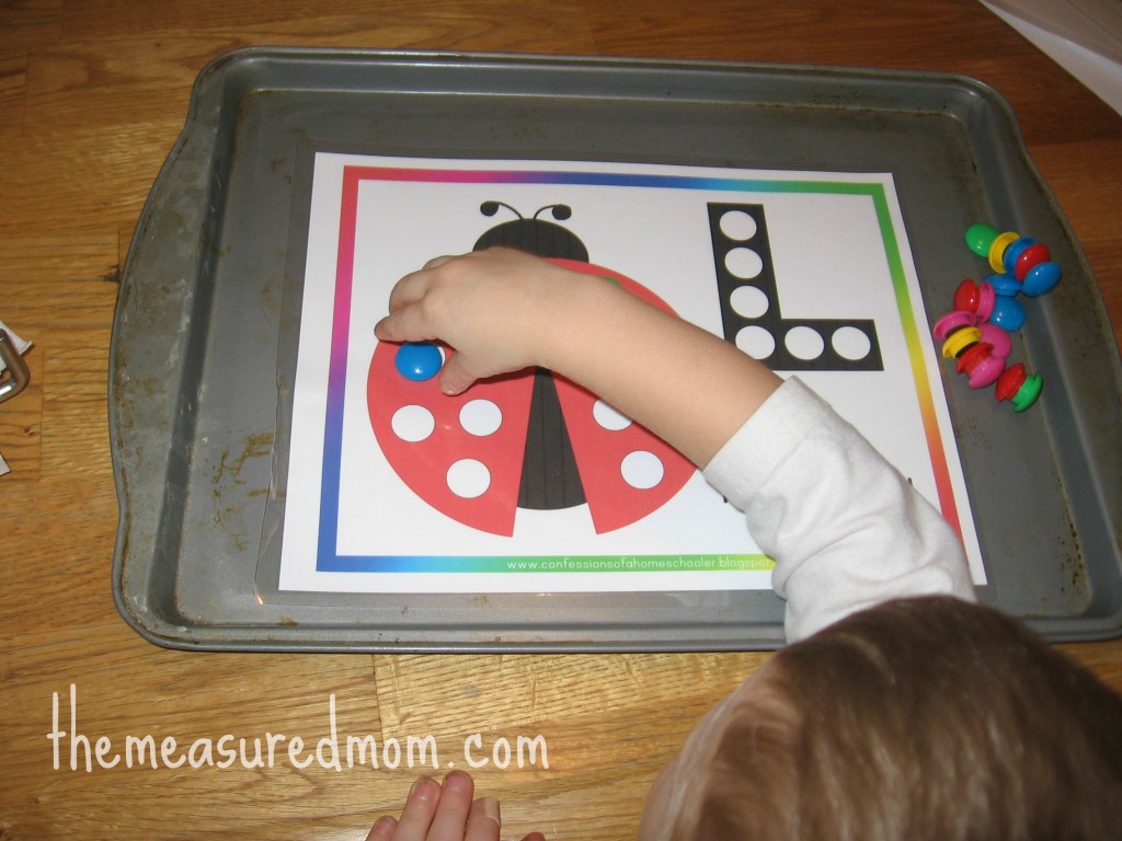 孩子将磁铁放在字母L的练习纸上